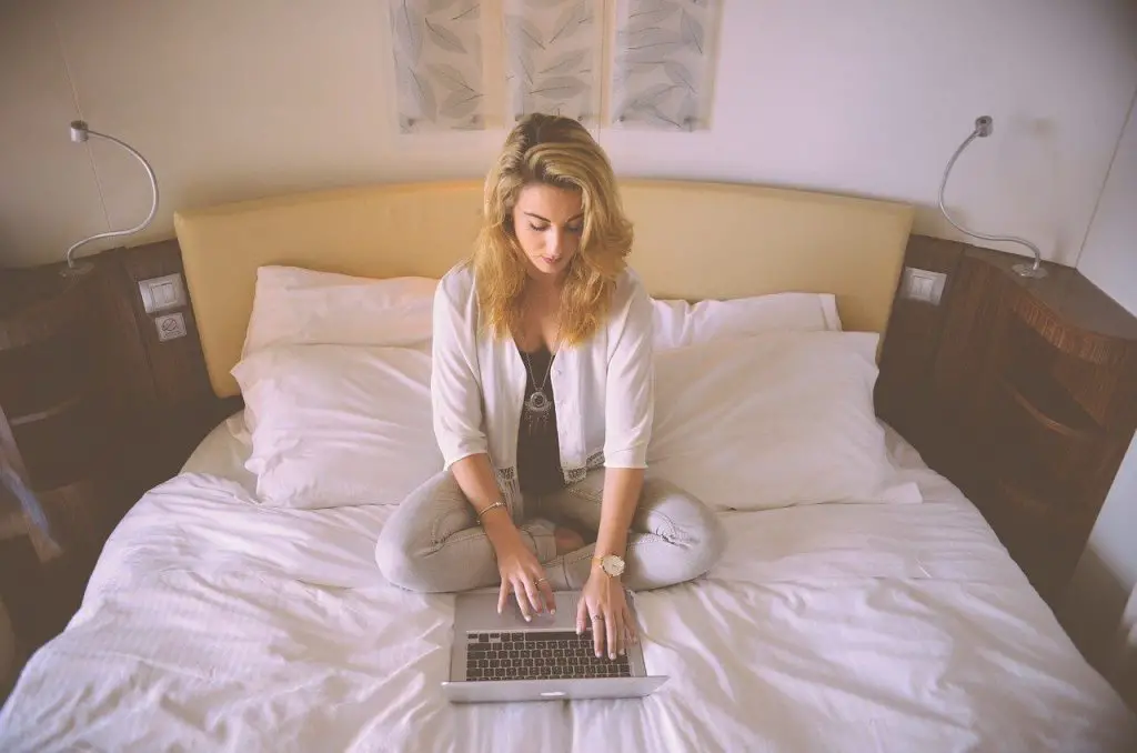 woman on bed with laptop earning